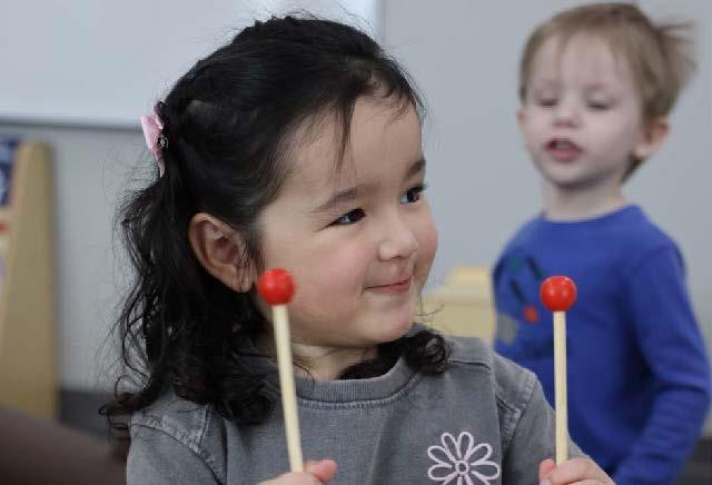 Preschool student Valentina Mata She is smiling while holding two xylophone sticks. 